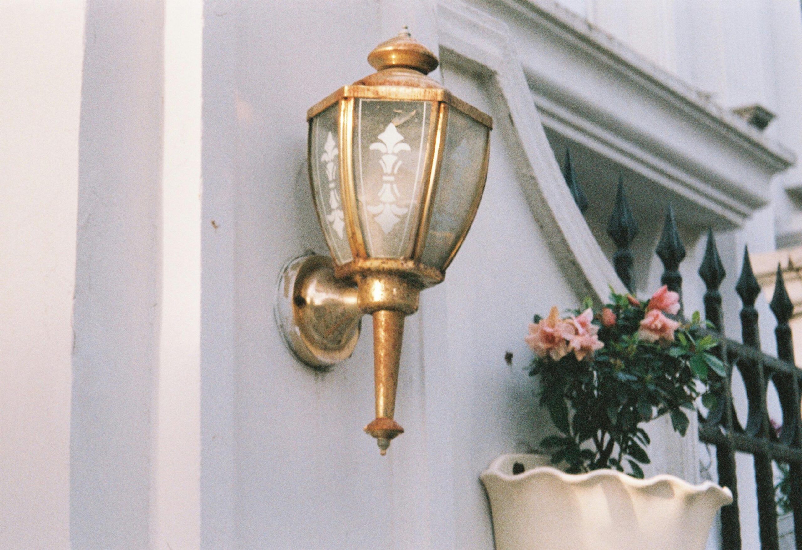 Elegant brass wall lantern with floral patterns and potted flowers, classic decor style.